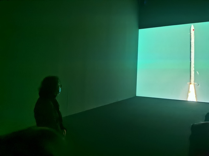 图11  导览时，徐冰观看“徐冰天书号”火箭发射实录影像  摄影 王诤