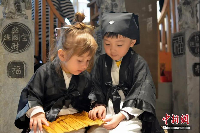 资料图：来自中外的萌娃身穿统一道服，手持竹简，在三清宫跟着道教师傅朗读《道德经》、《弟子规》。程希雪 摄