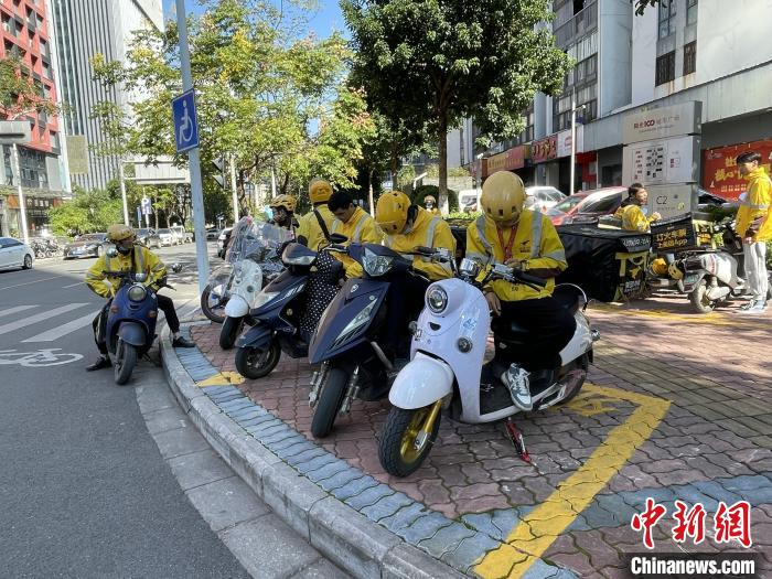 外卖骑手在人行道“专属”停车位上休息。　林馨 摄