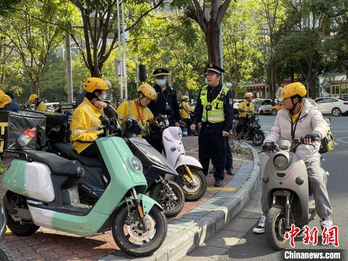 执法人员劝导外卖骑手在“专属”车位规范停车。　林馨 摄