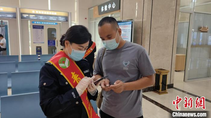 交警支队车管所“全国青年文明号”导办员引导民众下载手机交管“12123”APP，并进行自助办理。　郝明明 摄