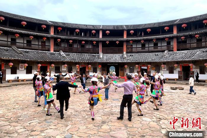 前来漳州参访的海外华文媒体代表在二宜楼内与景区工作人员跳舞互动。　王东明 摄