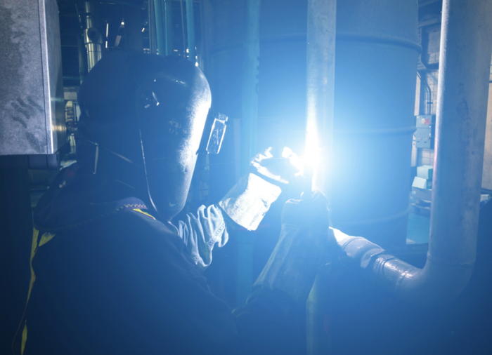 一位戴面罩的工人在用氩弧焊进行焊接。视觉中国供图