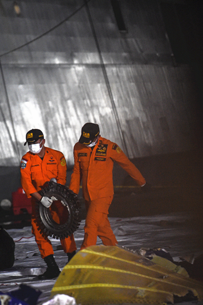 图说：1月10日，搜救人员在印度尼西亚雅加达戈戎不碌港搬运失事客机残骸。