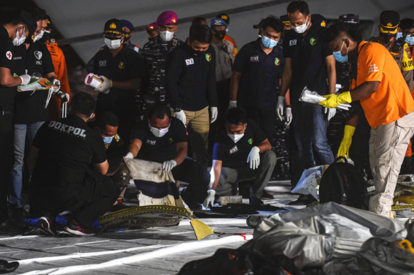 图说：1月10日，搜救人员在印度尼西亚雅加达戈戎不碌港查看遇难者衣物。新华社 发（阿贡 摄）（下同）