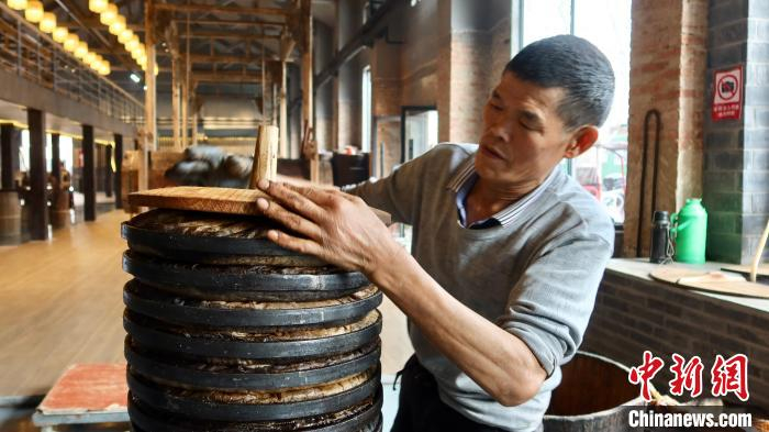 油茶师傅将水蒸后的油茶粉末压制成“茶饼”。　董易鑫 摄