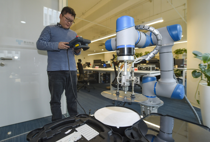 （泰治科技研发人员使用6轴工业机械手对晶圆进行搬运装盒操作）