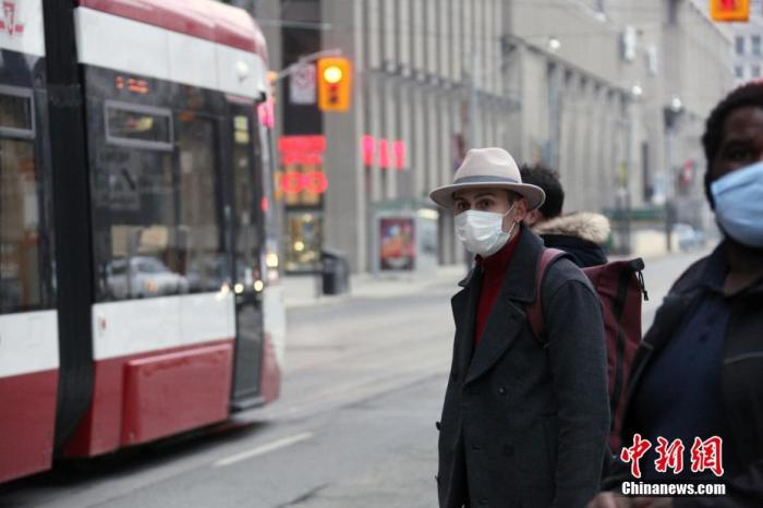 当地时间1月14日，佩戴口罩的乘客在加拿大多伦多市中心等候公交车。多伦多所在的加拿大人口第一大省安大略省从当天开始实施“居家令”。 中新社记者 余瑞冬 摄