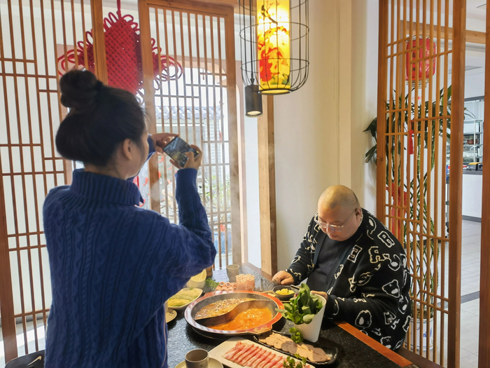 ▲11月25日，邱绍春和美食博主小语在一家火锅店拍摄短视频。新京报记者 李照 摄