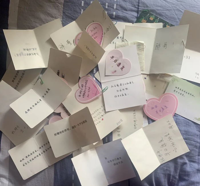 ▲邱绍春住院期间，网友送来的鲜花摆满了ICU门口，女友刘佳把所有网友的留言卡都珍藏起来。受访者供图