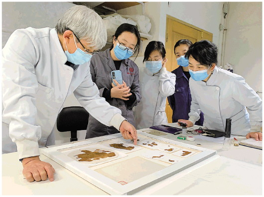 　　赵丰（左一）、周旸（右一）等在陕西省考古研究院研究法门寺出土丝绸。受访者供图