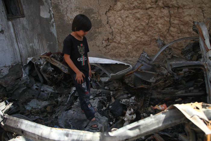  9月18日，在8月29日被美军无人机袭击的阿富汗喀布尔居民区，遇难者亲人站在汽车残骸上。新华社发（塞夫拉赫曼·萨菲摄）