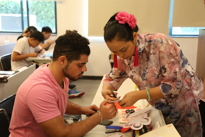 （佛山剪纸“非遗”传承人饶宝莲执教留学生剪纸课，学校供图，央广网发）