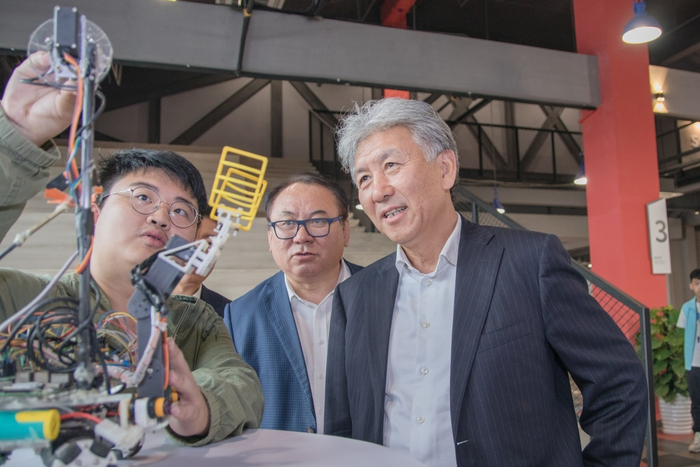 （学生为刘积仁董事长讲解科创作品《无人配送小车》，学校供图，央广网发）