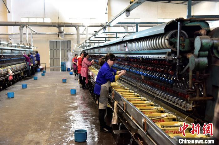     图为女工在车间从蚕茧中抽出蚕丝。　罗永皓　摄