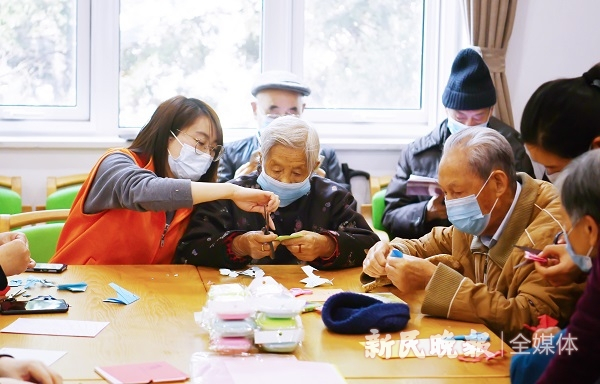 图说：志愿者教老人剪纸