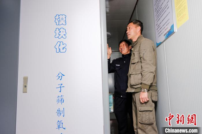 图为警务保障民警向供氧系统技术人员学习操作流程。　胡传鑫 摄