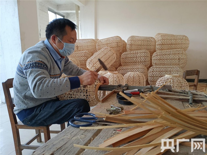 马武军正给竹灯罩固定笼口（央广网发 记者吴良艺摄）