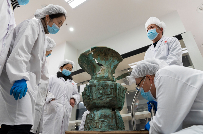 2021年12月23日，三星堆博物馆文物保护修复展示中心。郭汉中带领徒弟们仔细研究今年3月直播发掘的第一件重要文物青铜大口尊。新京报记者 郭延冰 摄