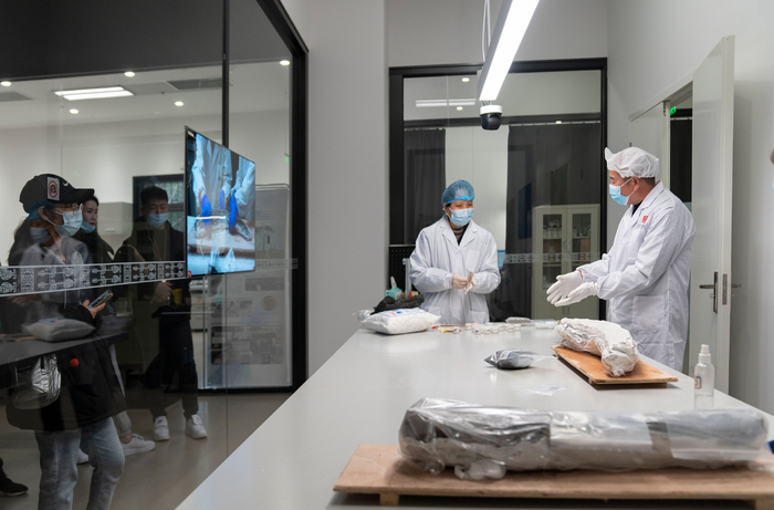 2021年12月23日，郭汉中在三星堆博物馆文物保护修复展示中心内指导徒弟们进行象牙修复工作，观众可以透过展示厅的玻璃观看修复过程。新京报记者 郭延冰 摄