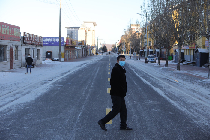 2021年12月12日，漠河，漠河舞厅老板李金宝行走在路上。当天，漠河全民核酸检测，街上人迹稀少。新京报记者 王嘉宁 摄