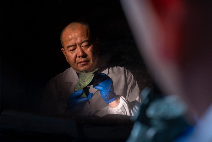 2021年12月23日，三星堆博物馆郭汉中文物修复创新工作室，郭汉中在聚光灯下研究大口尊肩部缺失牛首复制补配件。新京报记者 郭延冰 摄