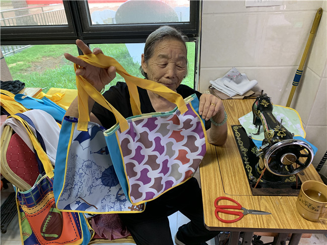▲海口市美兰区白沙门环保教育站83岁的志愿者赵月英展示亲手制作的各类环保袋。她用废旧布料缝制环保布袋，免费送给市民和游客，三年来已送出三千多个自制布袋。