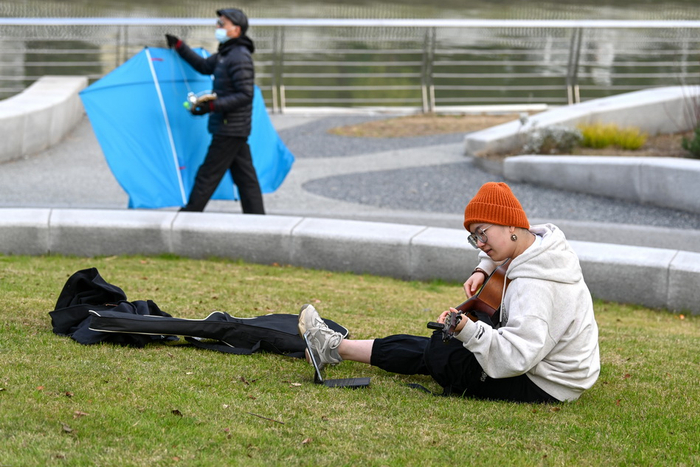 2021年12月11日，苏州河一号绿地，一位女孩在草地上弹吉他。