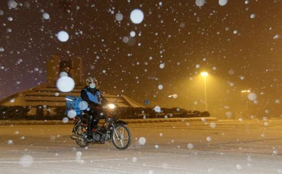 2021年1月25日，哈尔滨，临近半夜降下大雪，街头一片朦胧，一位外卖员正在雪中送餐。视觉中国供图