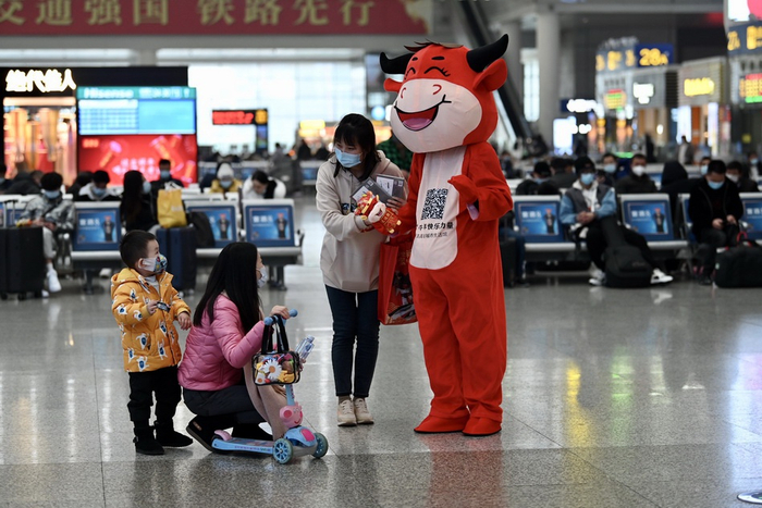 1月28日，上海虹桥火车站，穿着牛形人偶服的工作人员在与小乘客互动。