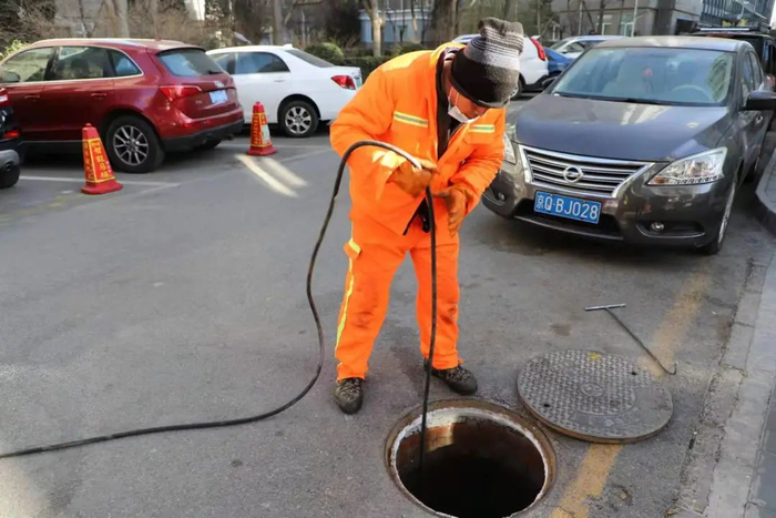 ▲畅柳园小区内，刘桂堂正在疏通管道。谢婧雯 摄