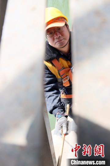 图为胡跃武悬空于大桥与河面之间检查钢结构拱脚。　王光辉 摄