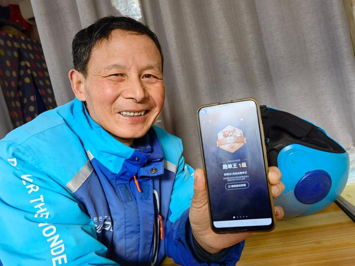 杨书生在展示他的“跑单王”荣誉勋章。 新华社记者 马姝瑞 摄