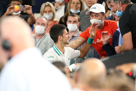     当地时间2月21日，德约科维奇夺得2021年澳网男单冠军后与观众席上的团队工作人员握手致意。视觉中国供图