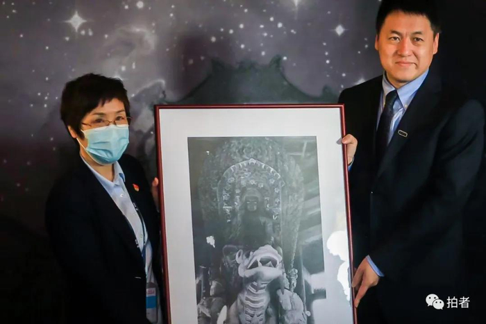 △ 北京史地民俗学会副会长刘阳（右）向圆明园管理处捐赠1920年正觉寺文殊亭文殊菩萨全身像电子版老照片一张，由圆明园档案馆收藏。