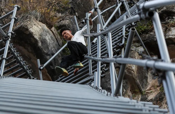 在四川省凉山彝族自治州昭觉县支尔莫乡阿土列尔村，某色拉博下钢梯，准备去接一名游客（2019年11月24日摄）。新华社记者 江宏景 摄