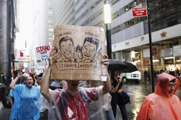△ 2011年9月29日，“占领华尔街”抗议活动的参加者在纽约金融区附近街头冒雨进行抗议。（新华社）