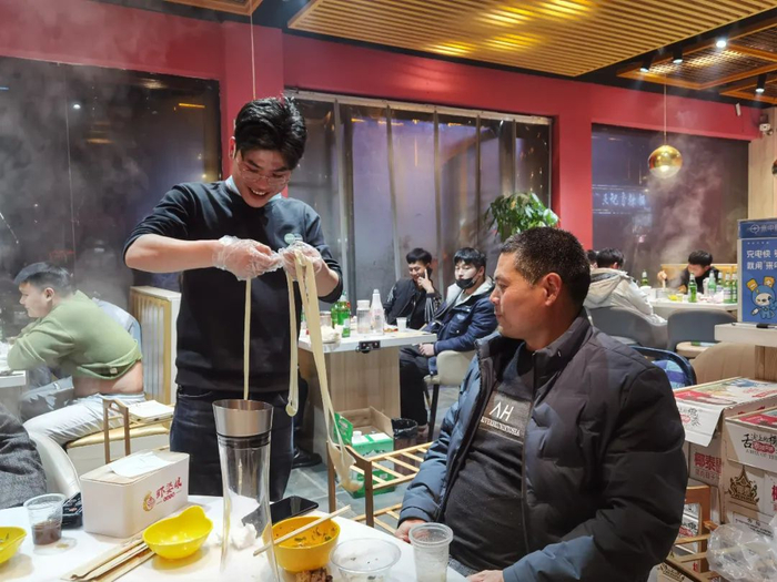 ▲吴春红和儿子在一起，儿子展示了拉面的技能。新京报记者 苑苏文 摄