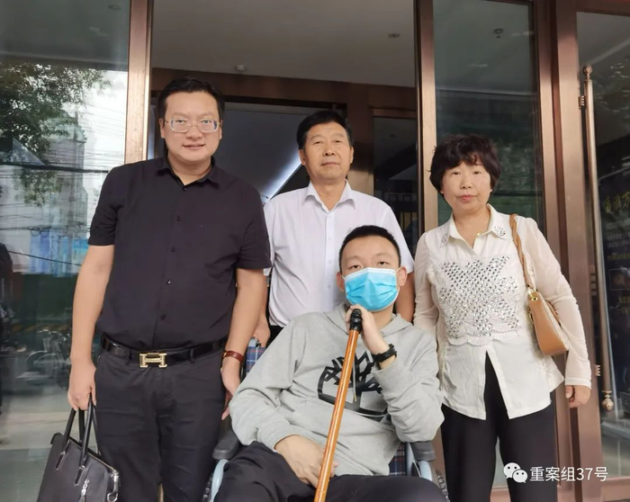 姚策坐在轮椅上和亲生父母及律师合影。受访者供图
