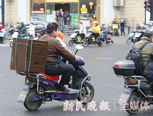 今天早高峰，斜土路宛平南路路口，一位非机动车骑手不仅未佩戴头盔，还把未成年小孩放在车前骑行。新民晚报记者 张龙 摄