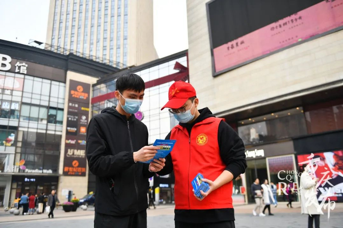 志愿者在街头宣传《重庆市文明行为促进条例》。邹乐 摄