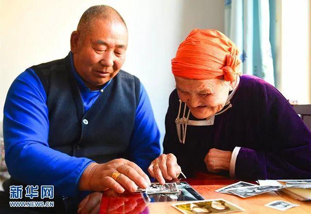 都贵玛（右）和她曾抚养过的扎拉嘎木在翻看老照片。图片来自新华网