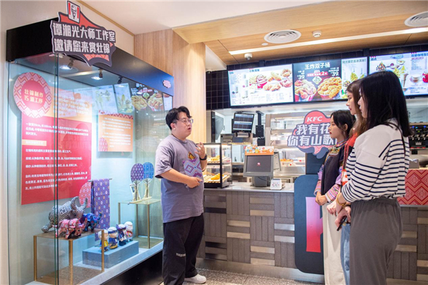 　　谭湘光大师工作室设计师向顾客们讲解壮族花纹的历史传说（央广网发 谈婕摄）