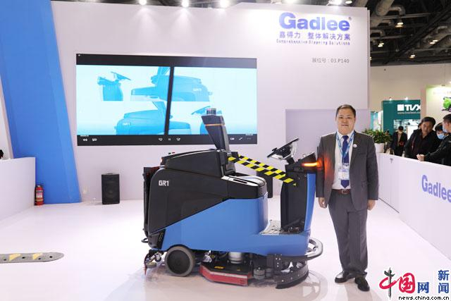 广东嘉得力副总经理郭超键与公司推出的全新无人驾驶洗地机合影。  中国网记者 苏向东/摄