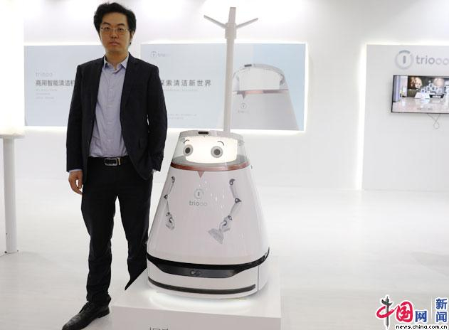 禧涤智能（北京）科技有限公司市场经理周润泽与公司推出的卡通造型清洁机器人合影。中国网记者 苏向东/摄