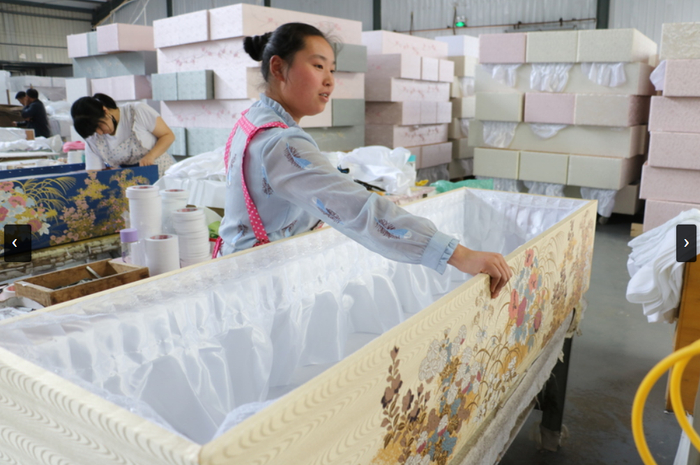 图源：新华社新闻，山东省菏泽市曹县庄寨镇德广木制品有限公司的一名员工正在准备布棺材。