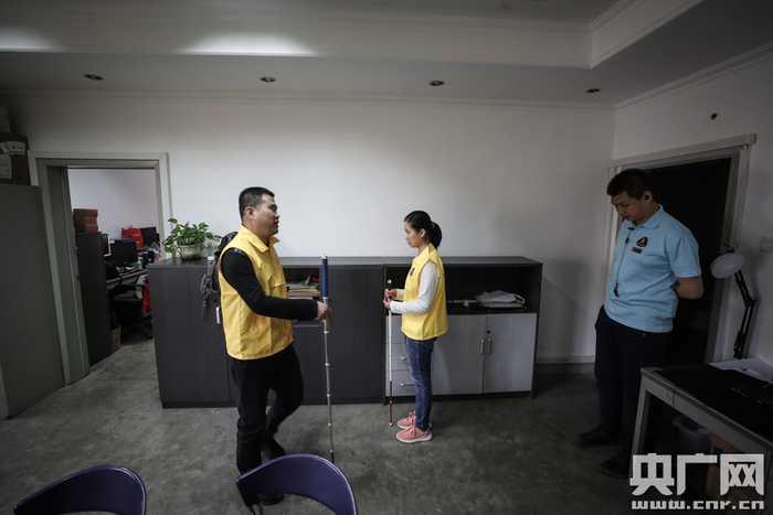 杨青风与助教余素一（右一）在指导学员使用盲杖（央广网记者 韩靖 摄）