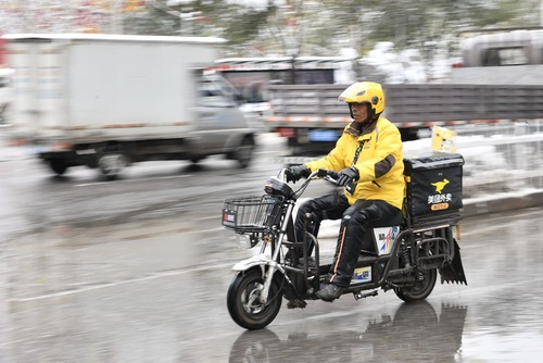 外卖骑手在雪后湿滑路面上骑行。新华社发（张龙 摄）
