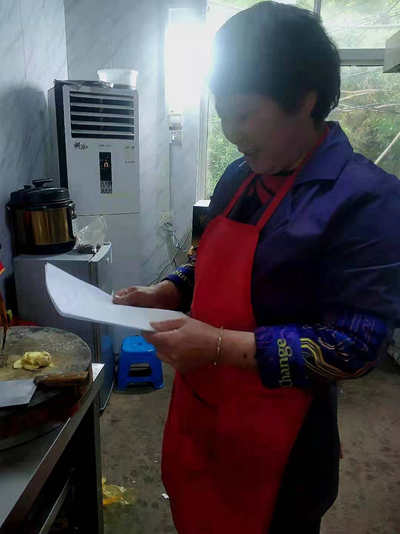     韩仕梅在厨房看自己写的诗。受访者供图