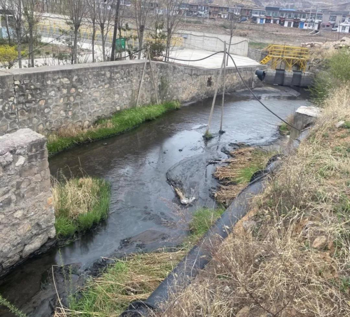 斜沟煤矿排污渠内有明显煤泥堆积现象，水面上浮有油花。生态环境部供图